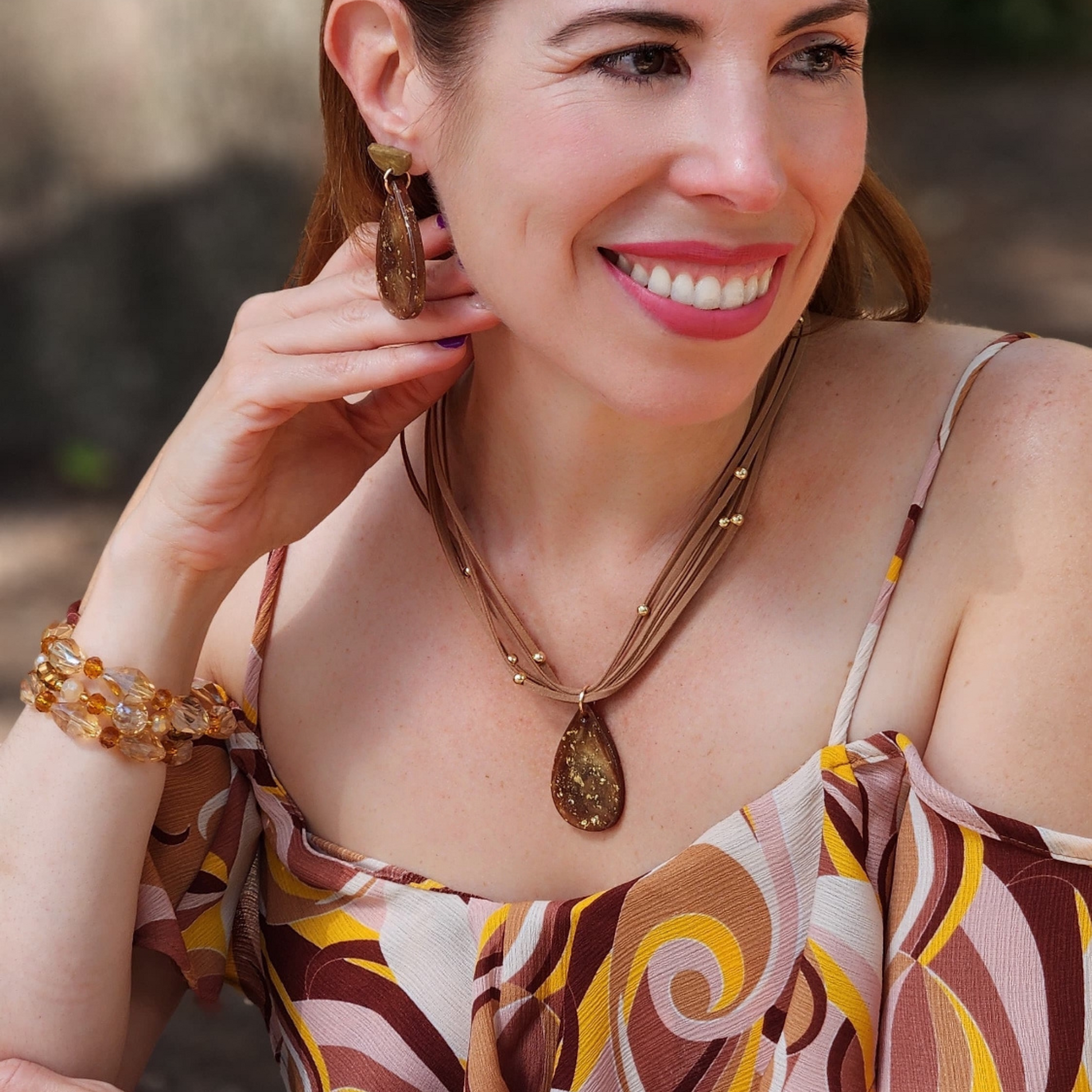 Woman wearing a patterned top and jewelry outdoors. Sherami Collection Fall Collection