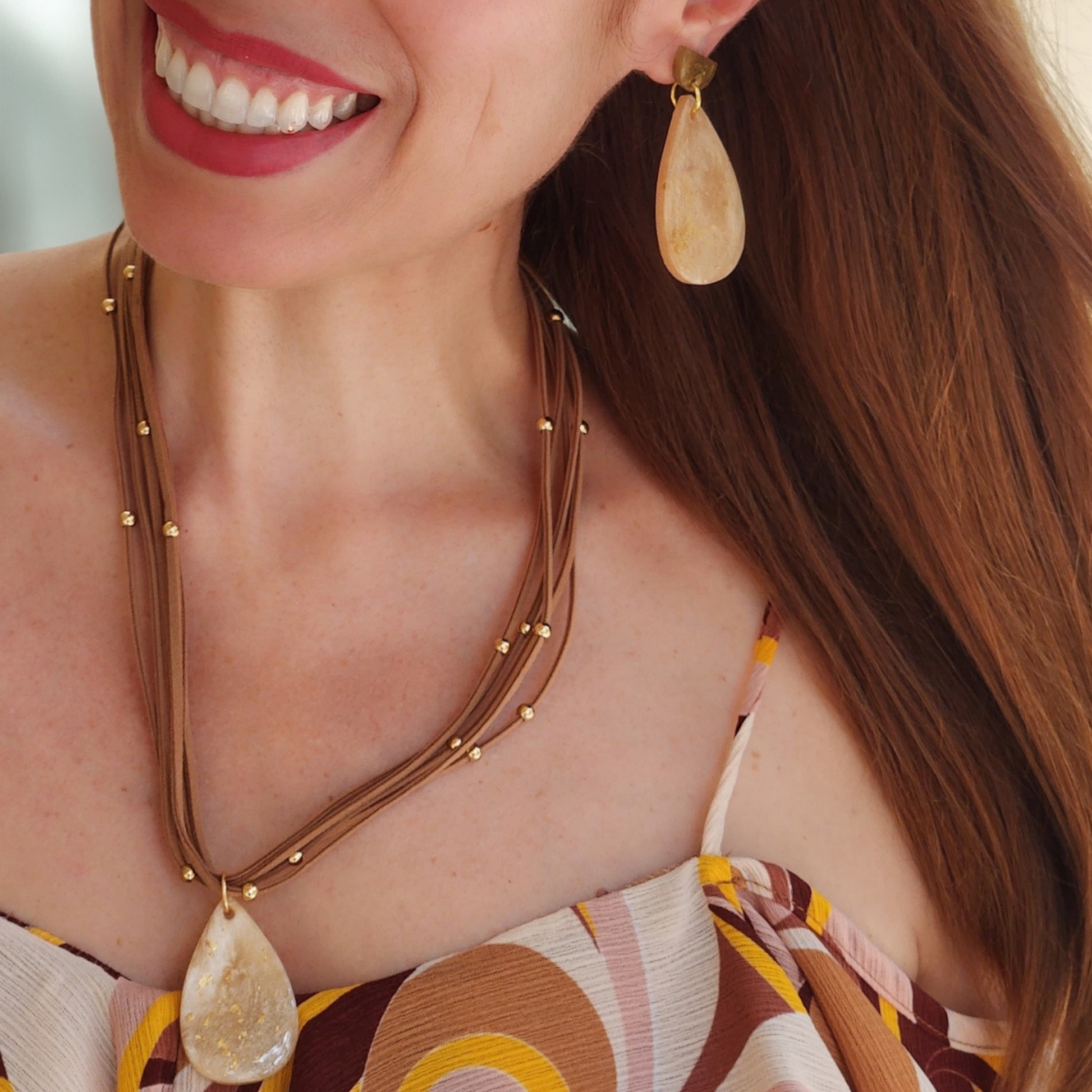 Woman wearing a necklace and earrings with a blurred background. Sherami Collection Fall Collection