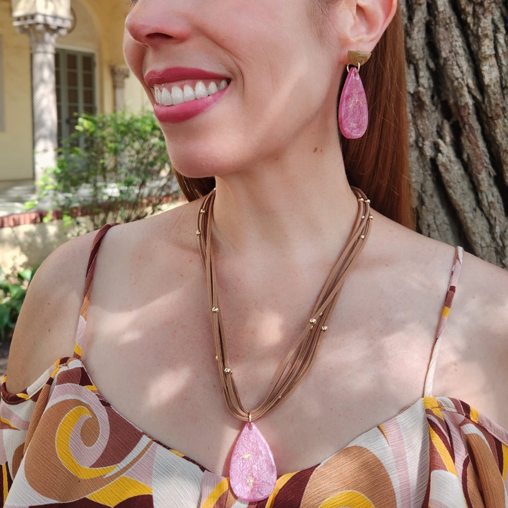 Woman wearing a necklace and pink earrings outdoors