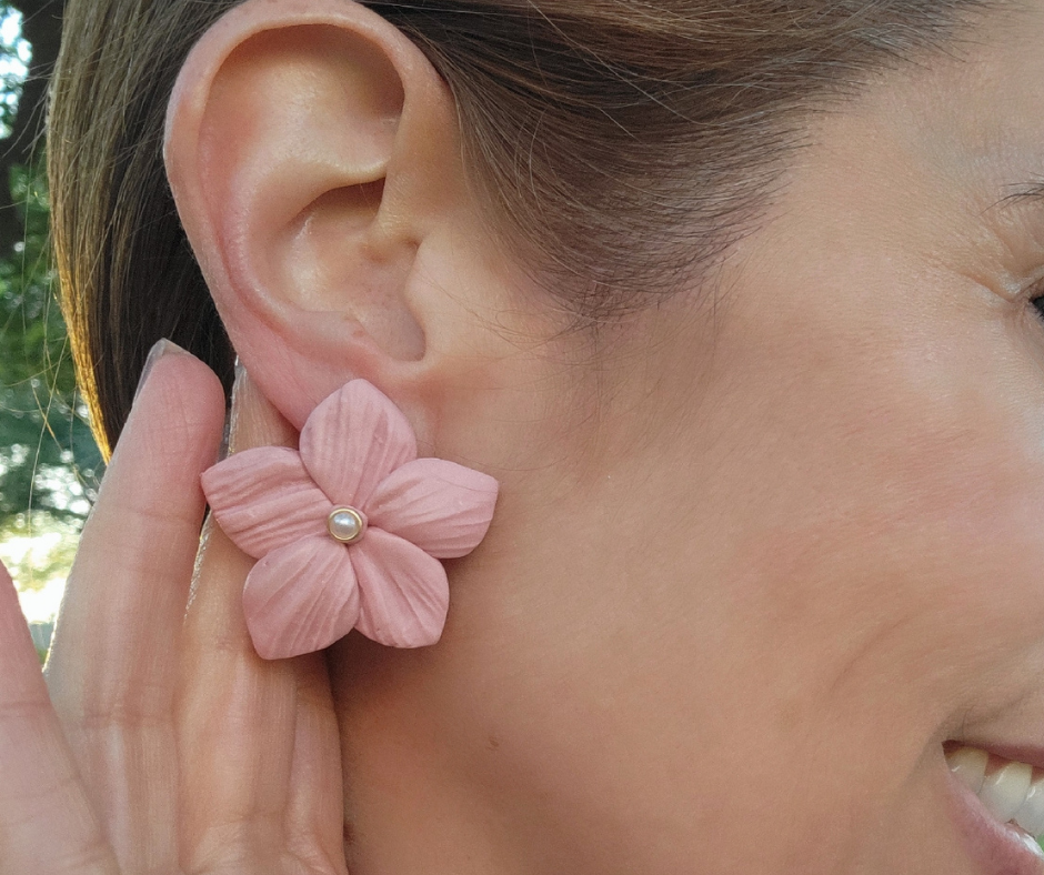 Aretes en forma de flor con textura y una perla en el centro.