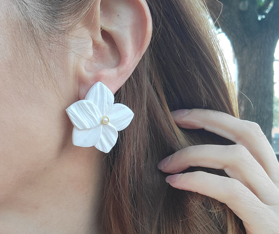 Aretes en forma de flor con textura y una perla en el centro.