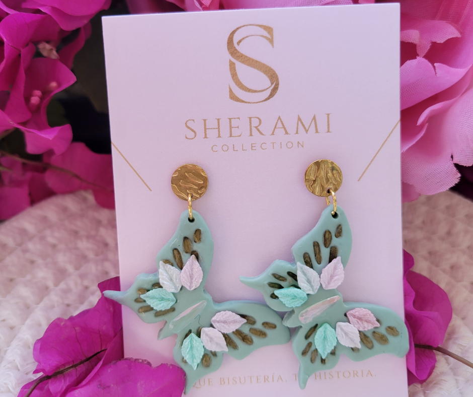 Aretes verse claro en forma de mariposa con detalles primaverales y gancho dorado.
