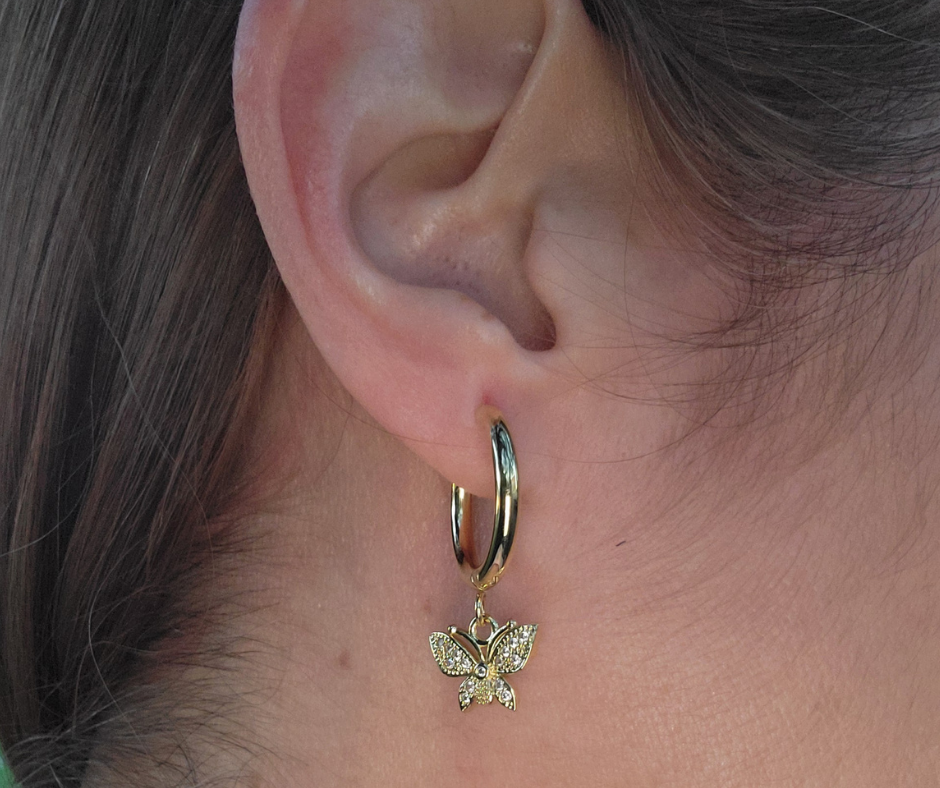 Aretes dorados tipo Huggies con colgante de mariposa 