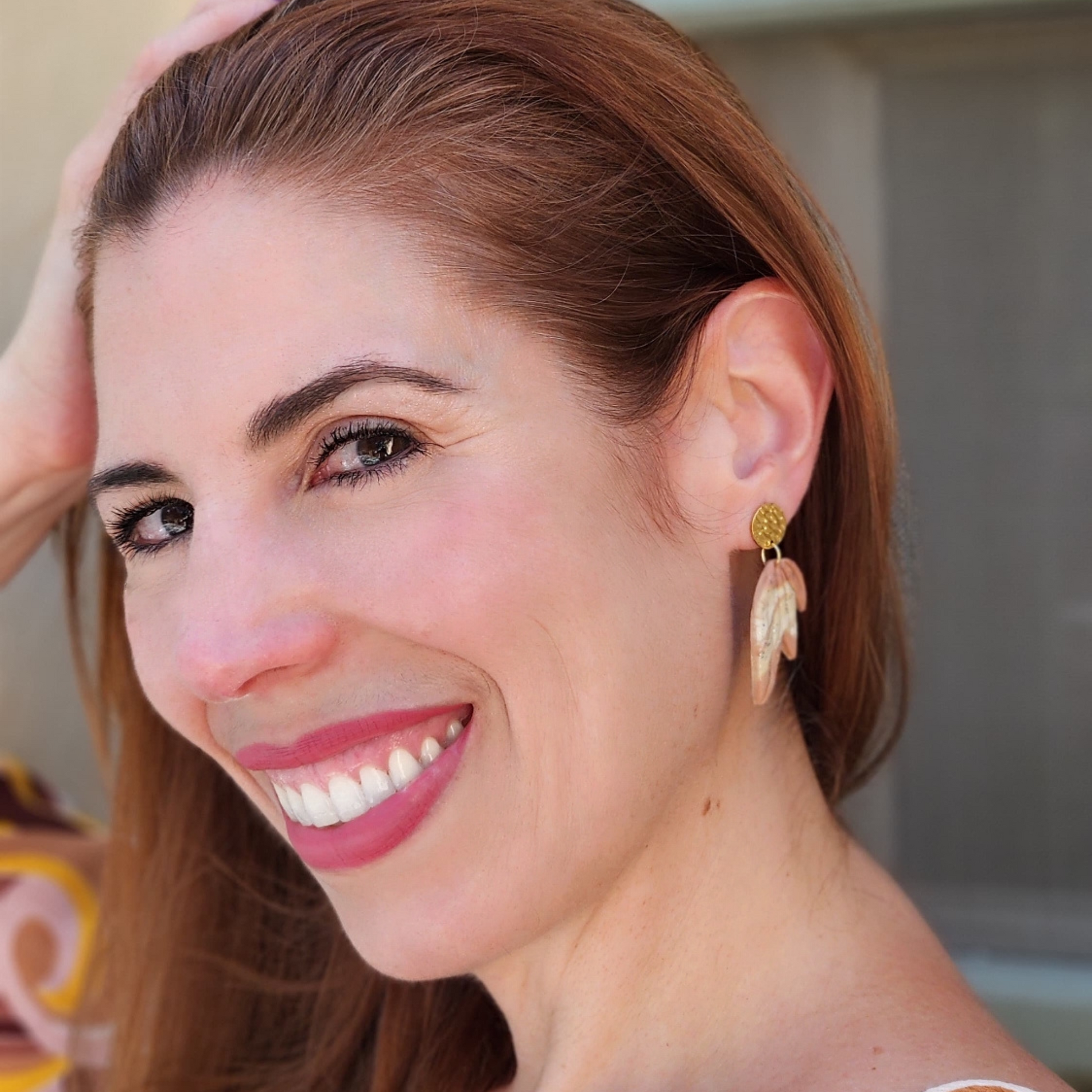 Mujere con aretes artesanales hechos en arcilla de Sherami Collection
