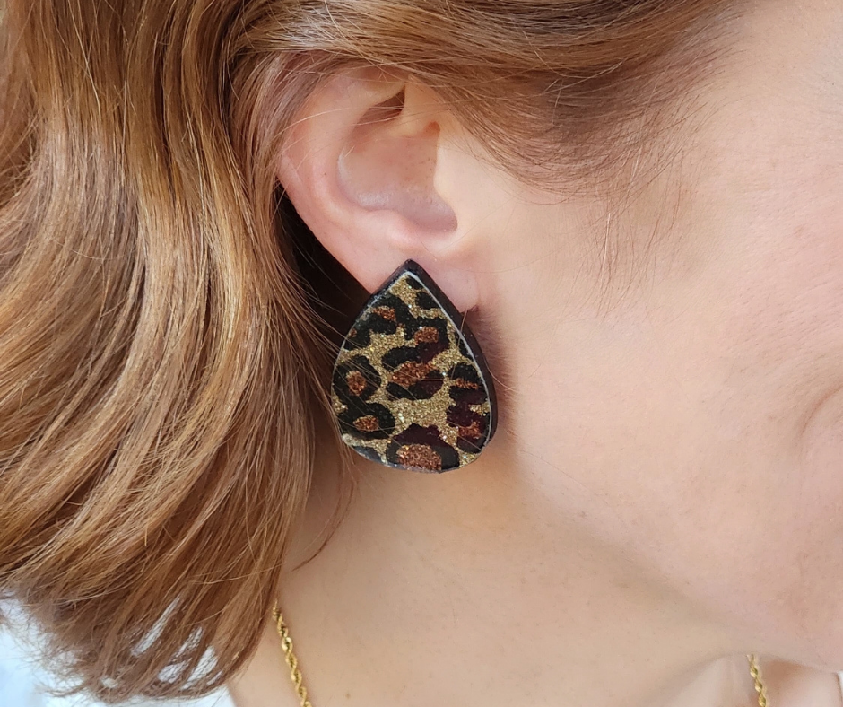 Primer plano de aretes de Sherami Collection  con estampado animal de cheetah con destellos dorados