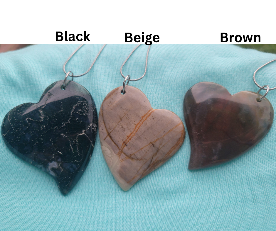 Three heart-shaped stone pendants in black, beige, and brown on a light blue background.