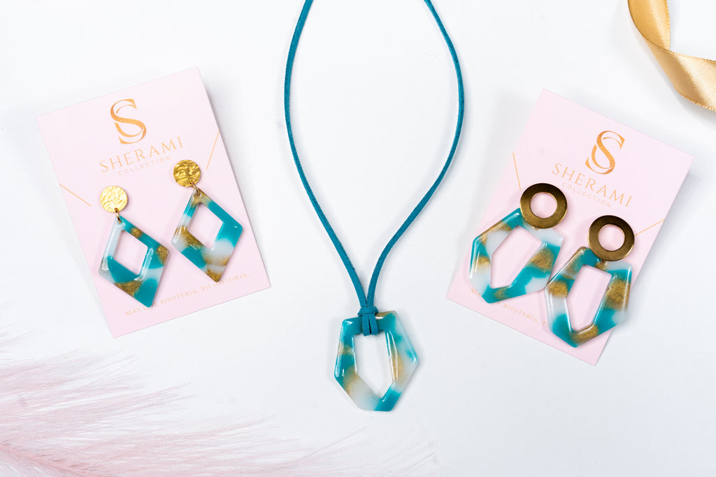Necklace and earrings with blue, white and gold design on pink cards with 'Sherami Collection' branding.