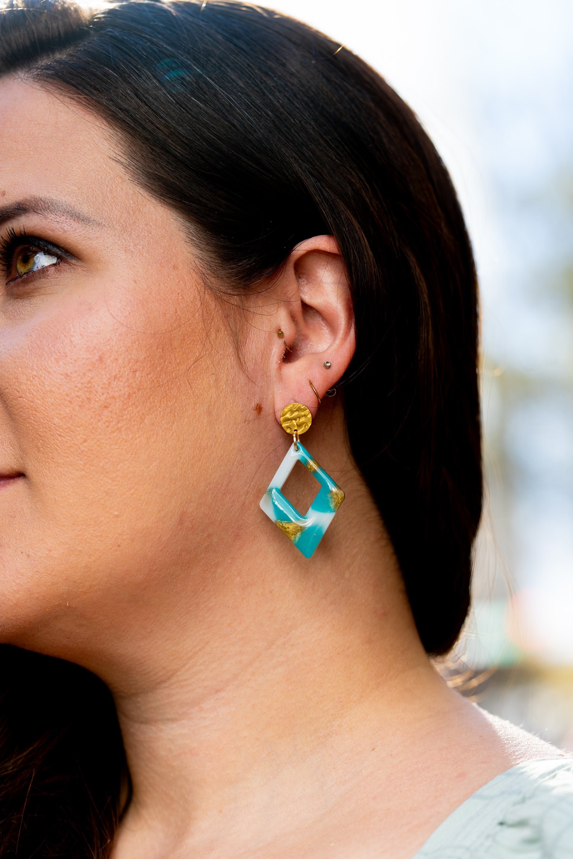 Close-up of a person wearing a pair of Sherami Collection blue, white and gold earring 