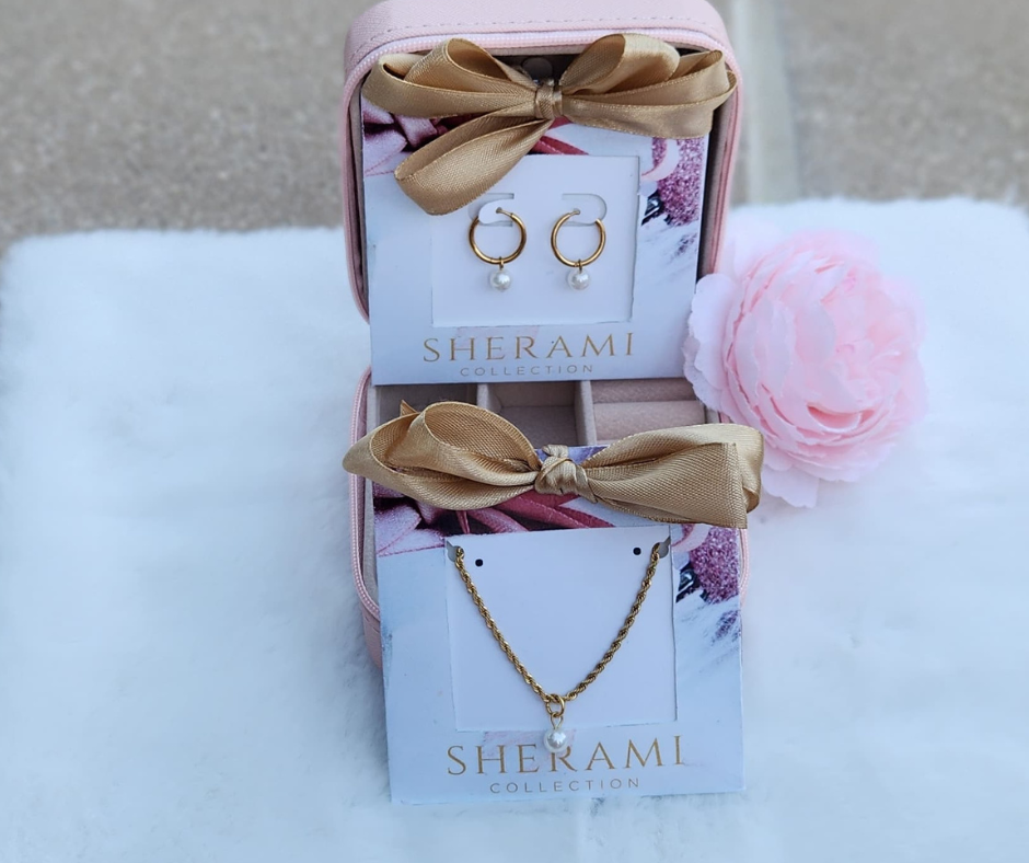 Primer plano de los aretes huggies con perla y la cadena de acero inoxidable con perla en empaque de regalo. 