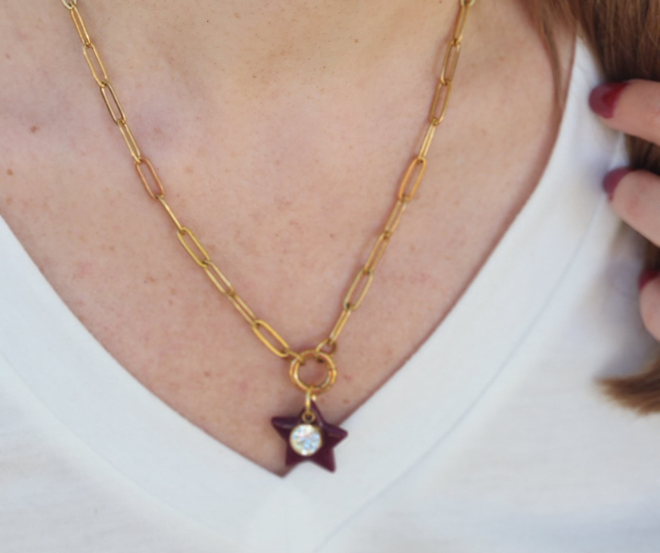 Primer plano del collar de eslabones dorado con estrella vino y circonia de Sherami Collection.