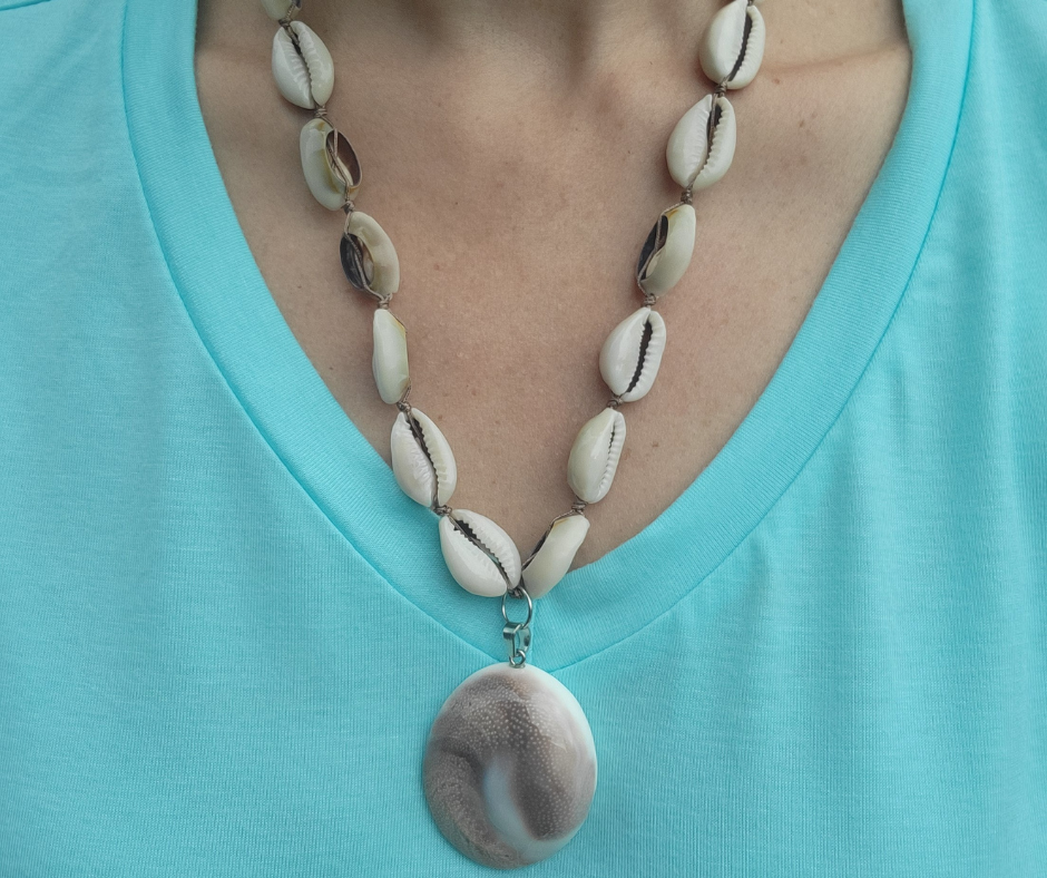 Necklace with shell beads and pendant on a turquoise shirt from Sherami Collection