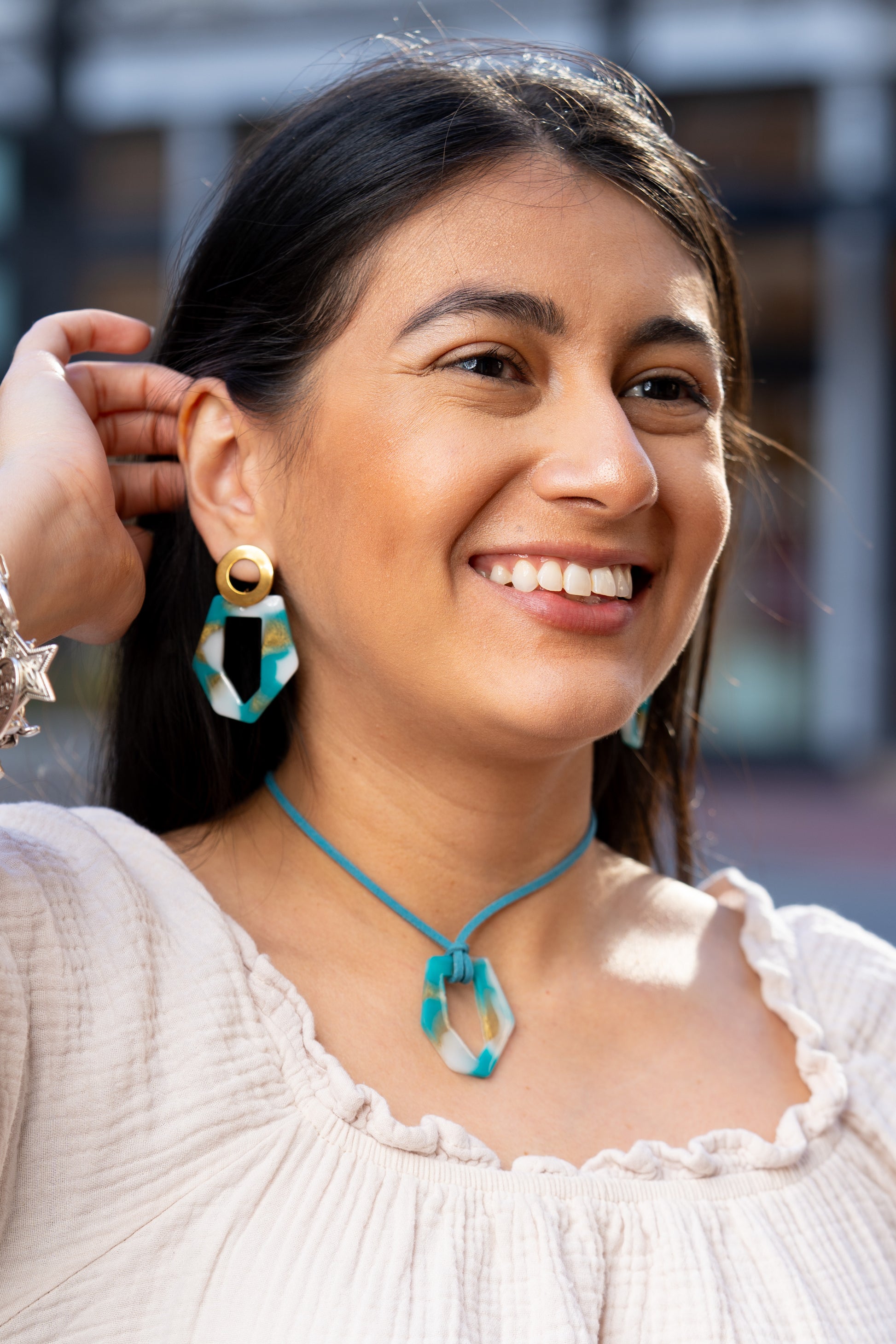 Mujer con aretes artesanales azul, blanco y dorado con collar a juego