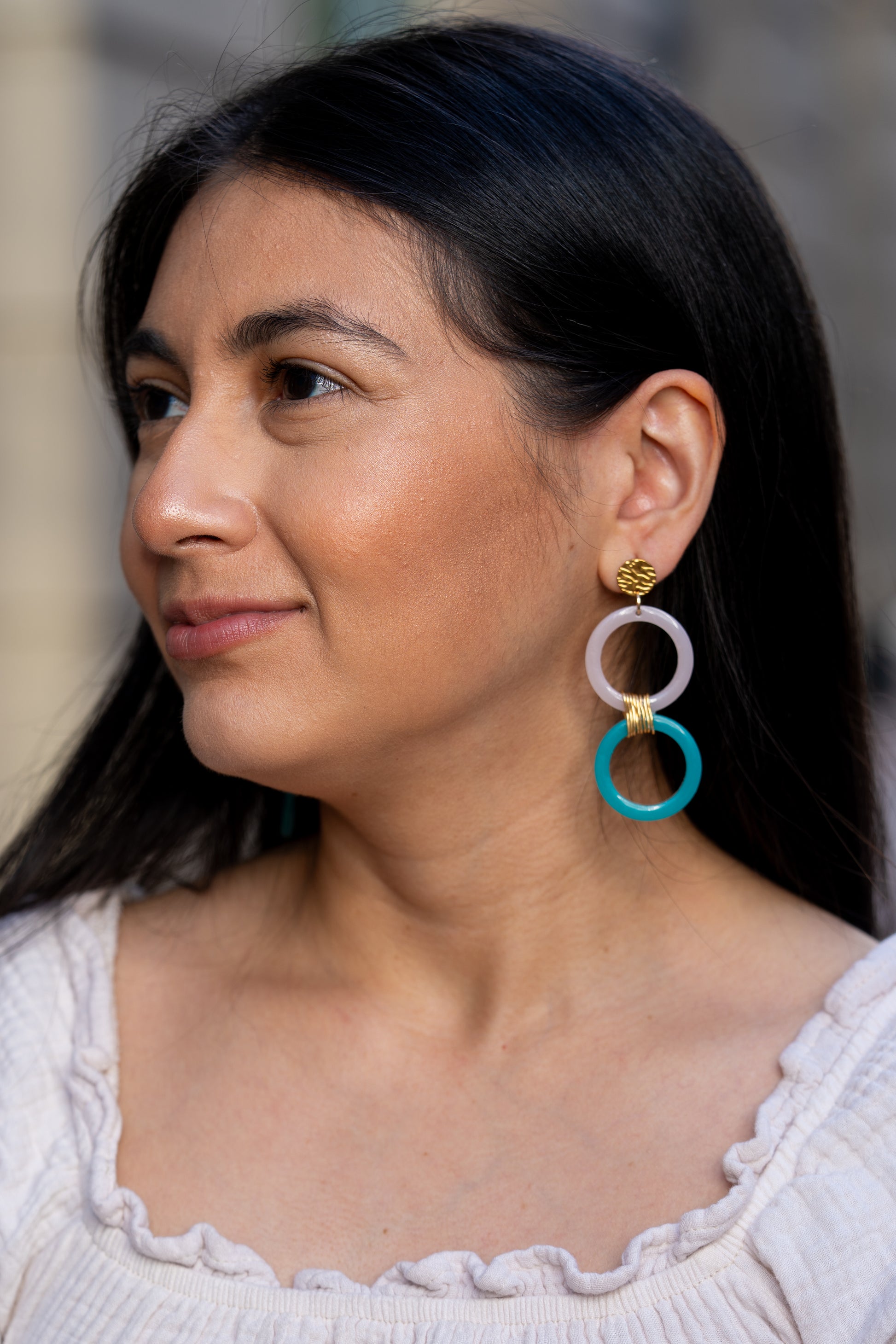 Primer plano de una mujer con pendientes de Sherami Collection  de colores con un fondo borroso