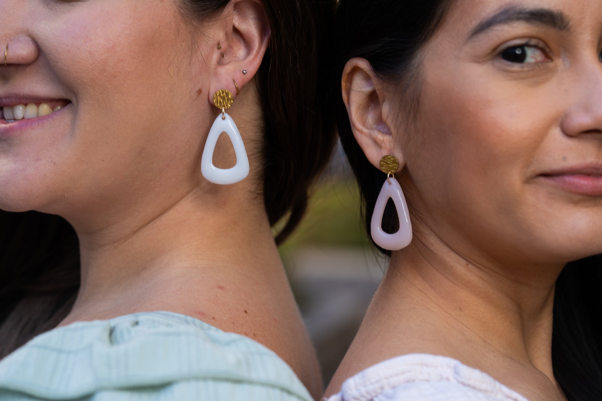 Two women wearing Sherami Collection earrings with a blurred background