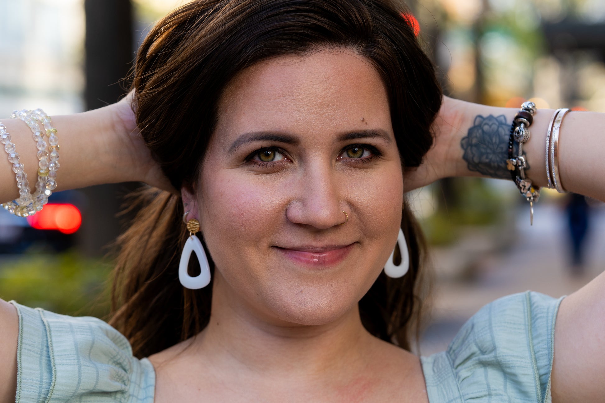 Woman with hands behind head wearing Sherami Collection earrings  outdoors