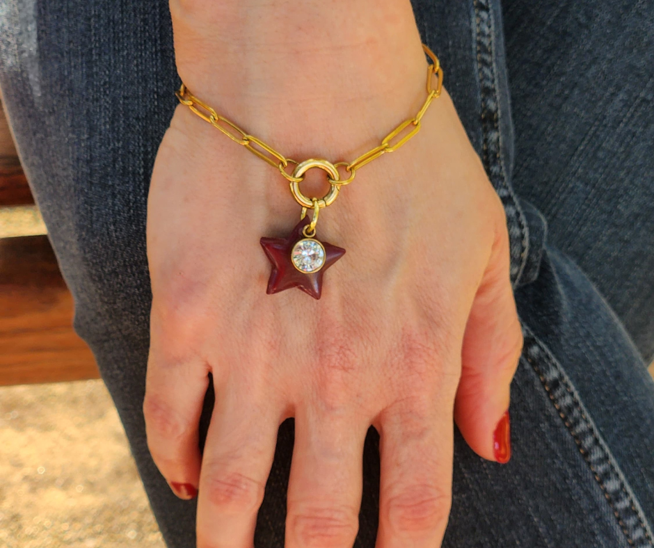 Primer plano de la pulsera de eslabones doada con estrella hecha a mano en color vino de Sherami Collection.