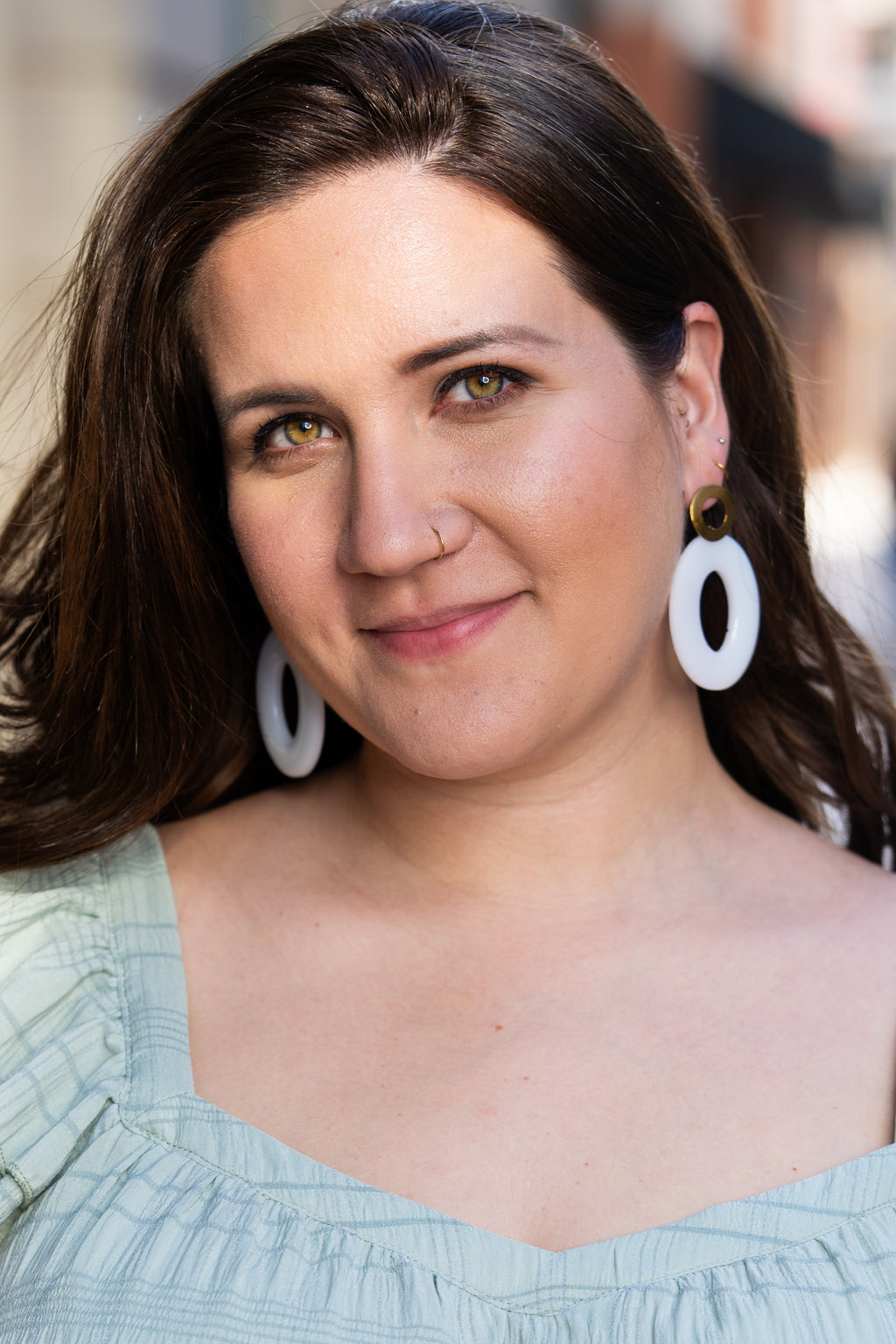 Woman wearing Sherami Collection white earrings, looking directly at the camera.
