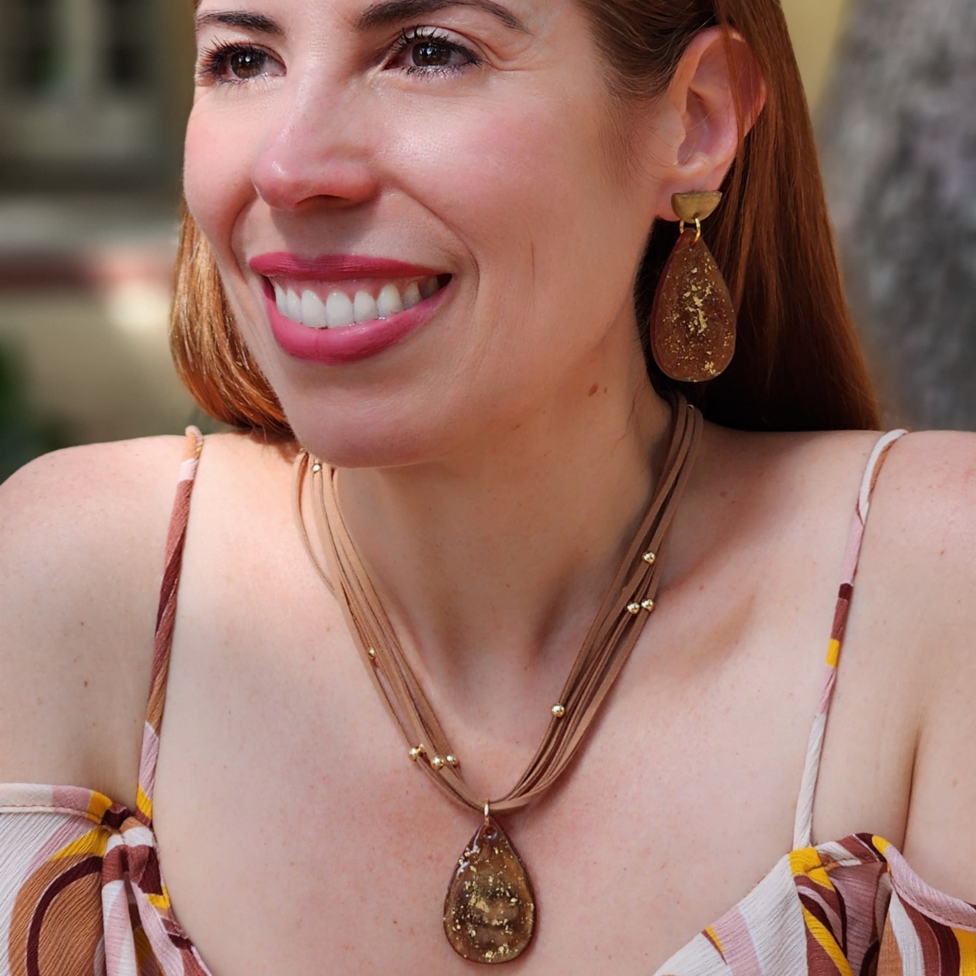 Mujer mostrando un conjunto de collar y aretes artesanales en color marrón de Sherami Collection
