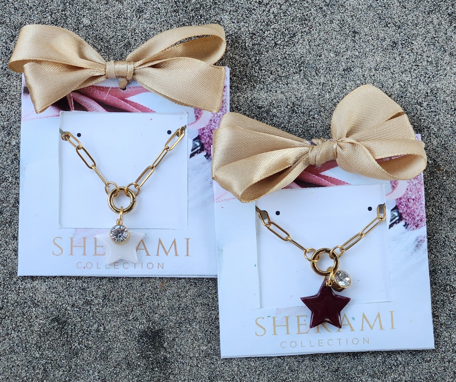 Collares dorados con estrella en blanca y vino de Sherami Collection en su empaque de regalo.