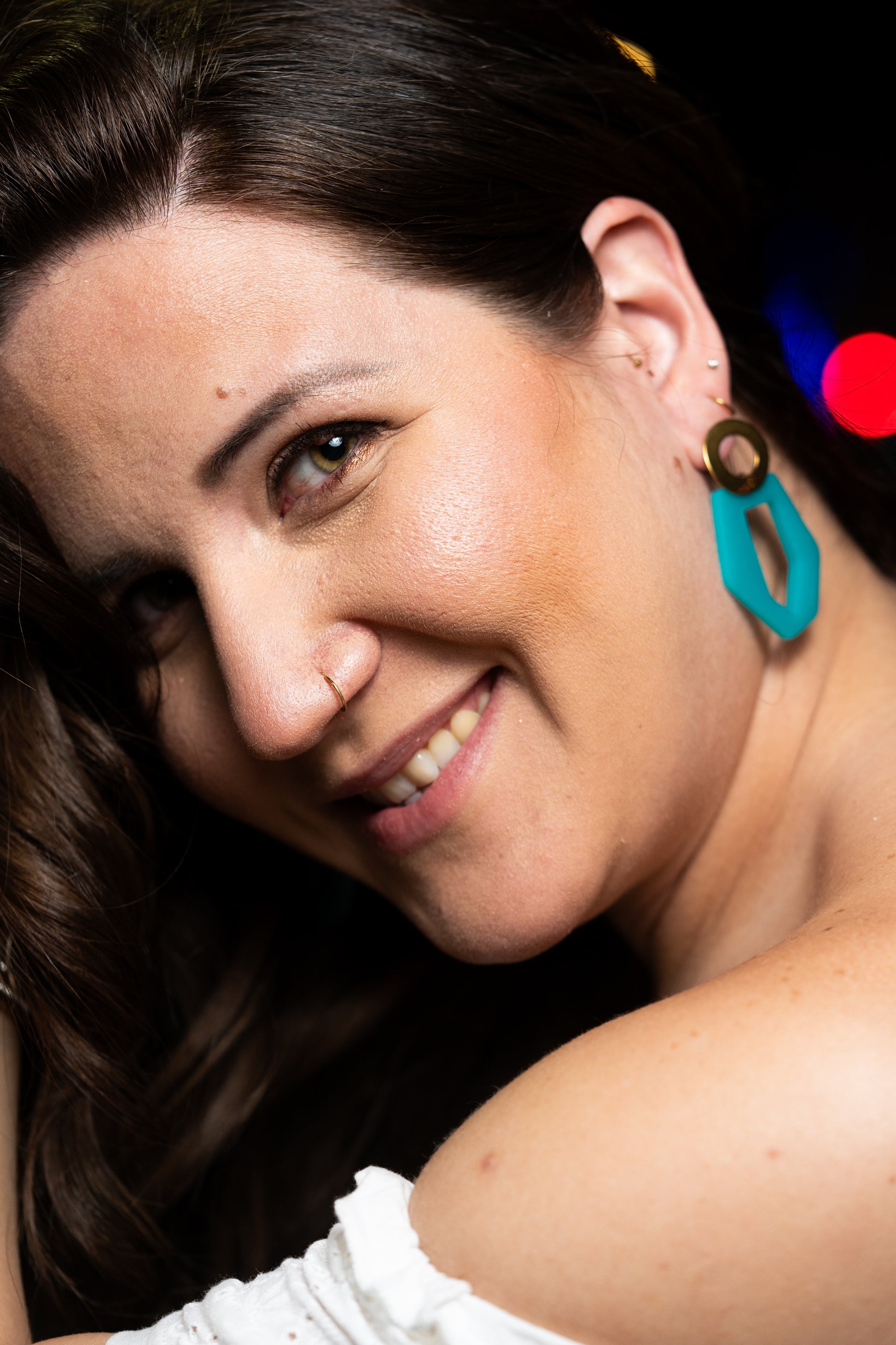 Close-up of a woman wearing turquoise earrings from Sherami Collection with a blurred background