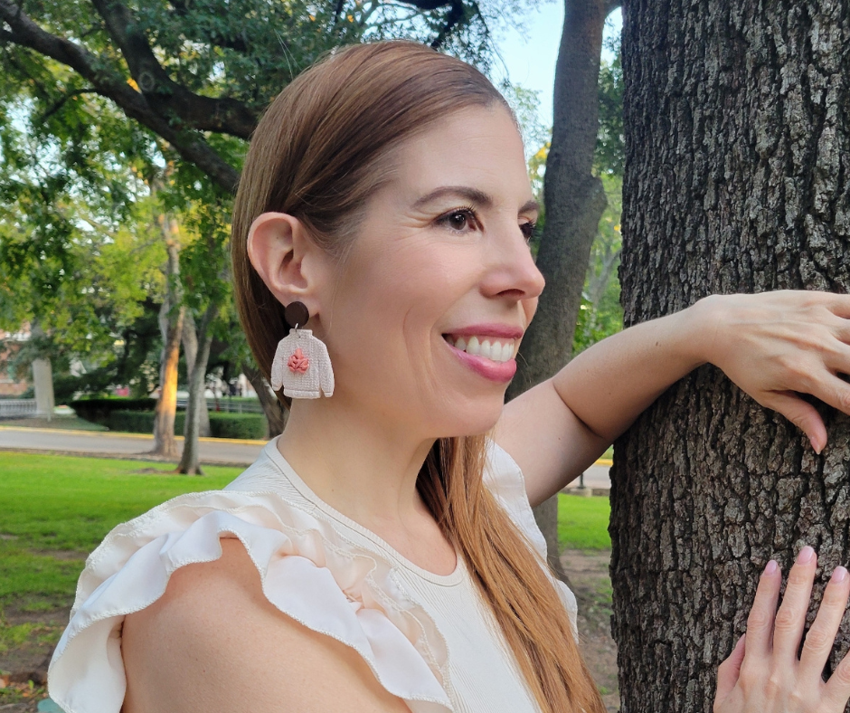 Aretes en forma de sueter sobre una modelo para que se pueda apeciar el tamaño ya puesto.